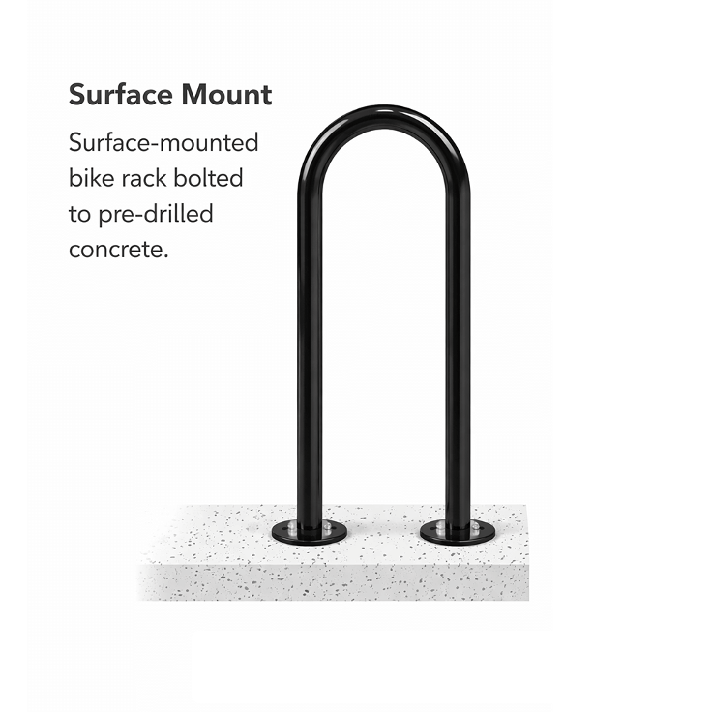 Surface-mounted loop bike rack bolted to concrete pavement, designed for secure and stable commercial bicycle parking.